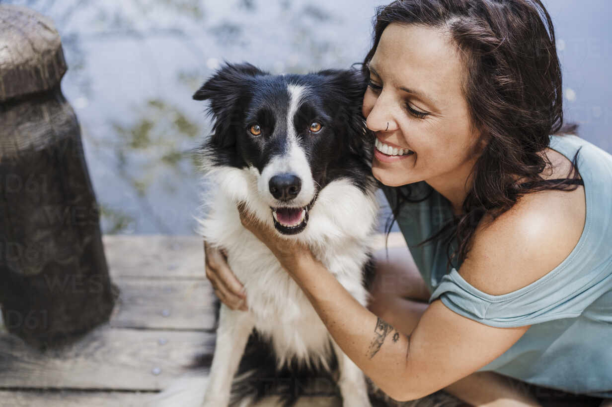files/happy-woman-hugging-dog-while-sitting-on-pier-EBBF04447.jpg